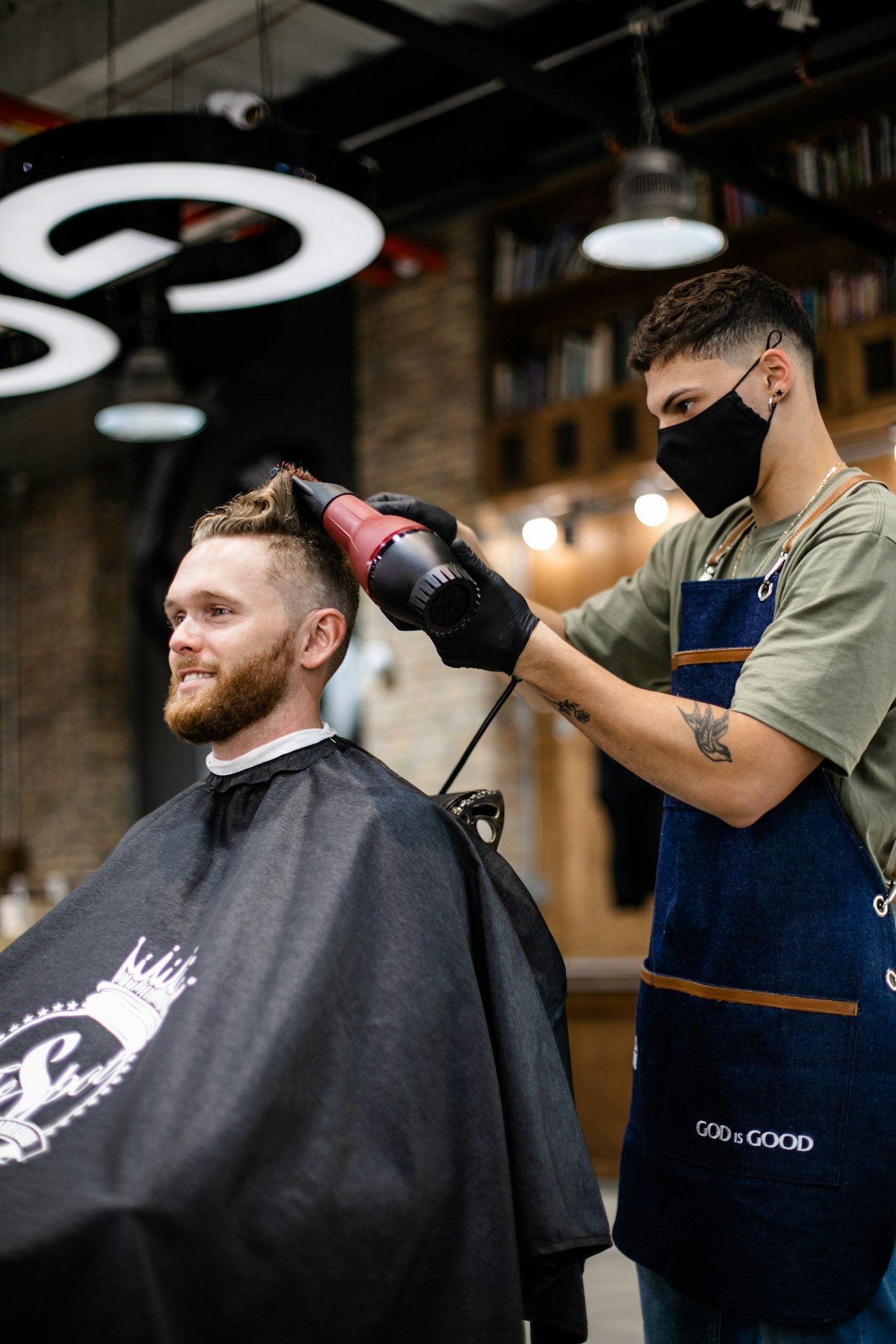 Barber styling a client's hair in an industrial loft-style space
