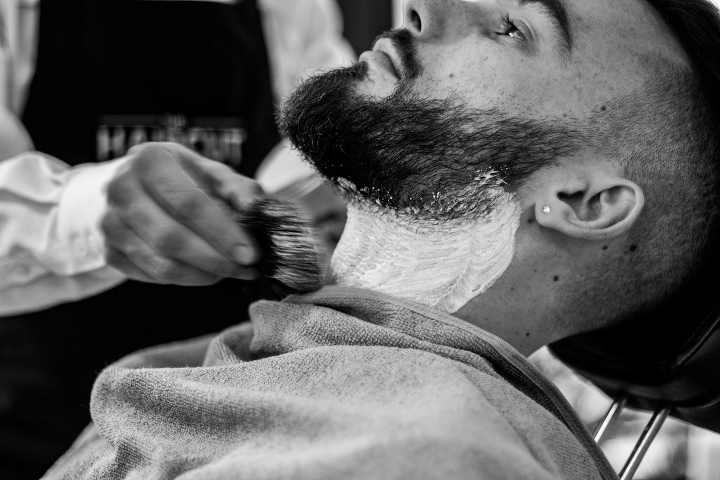 Barber carefully shaving a client's beard with a straight razor