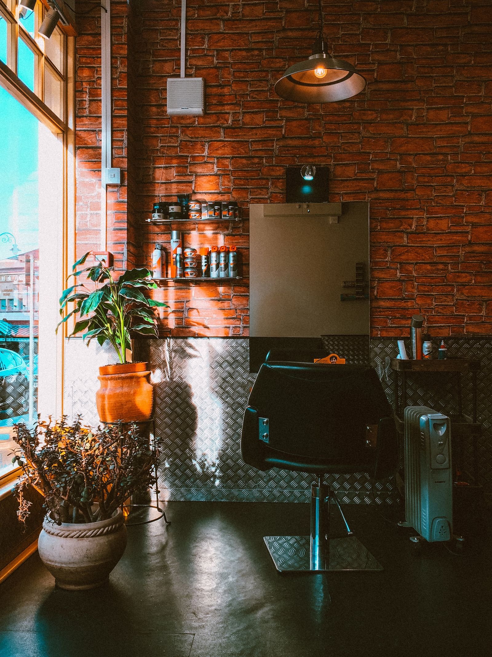Warm, inviting salon corner with exposed brick, a vintage chair, and greenery