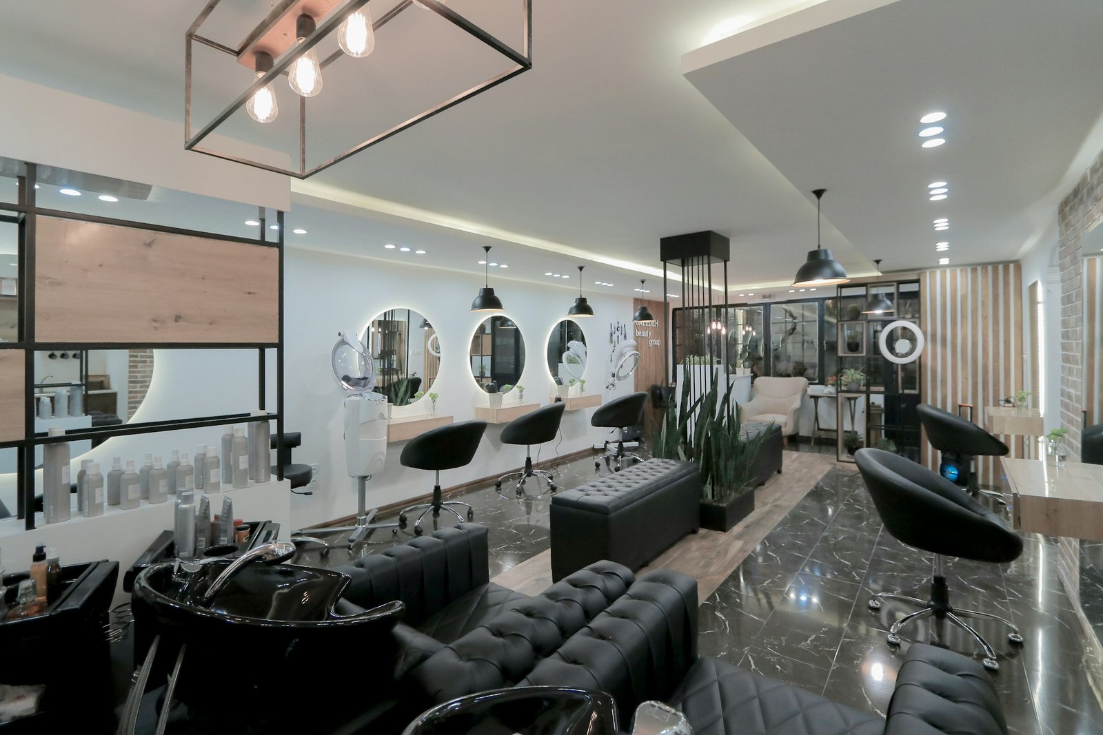 Luxurious salon lounge with tufted black chairs, round mirrors, and warm lighting