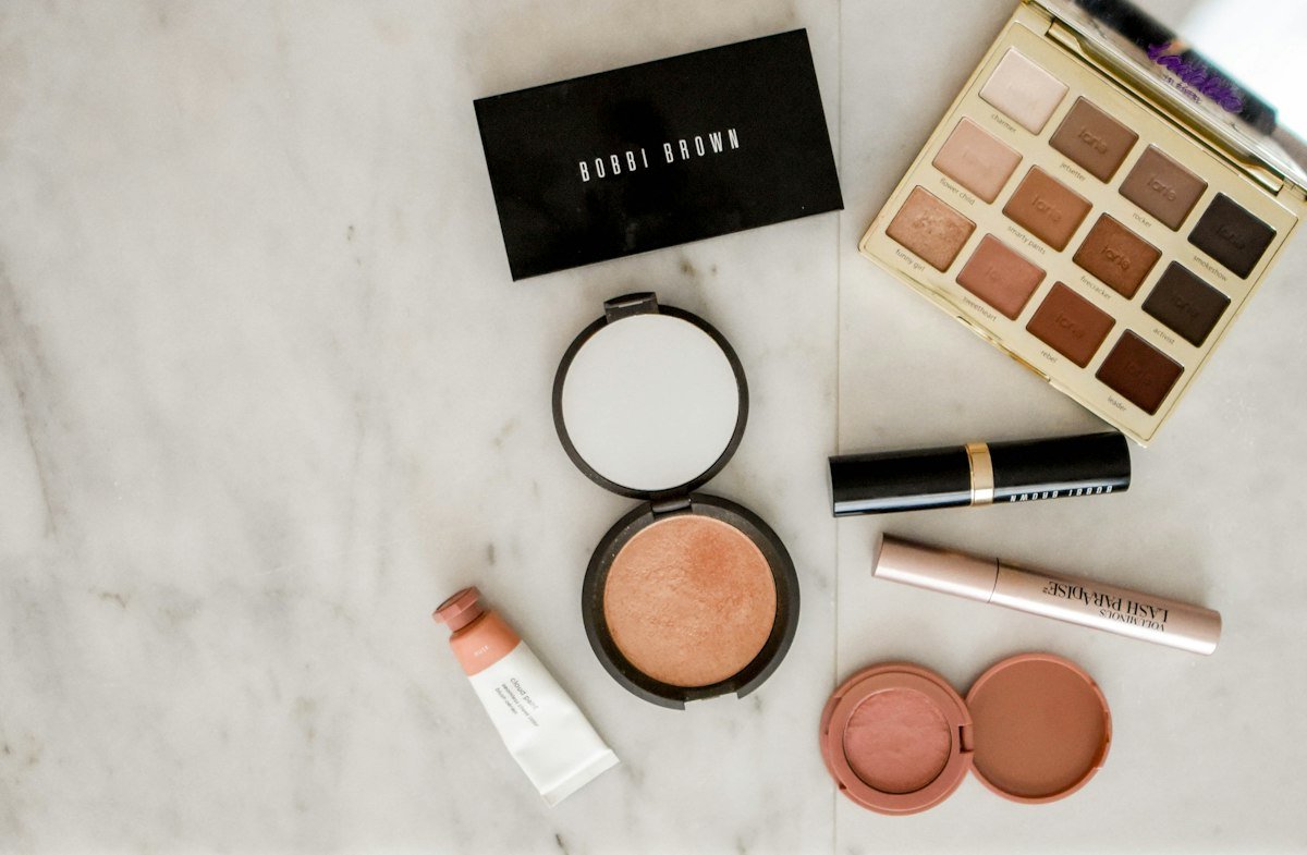 Beauty products arranged on a marble surface in warm gold tones